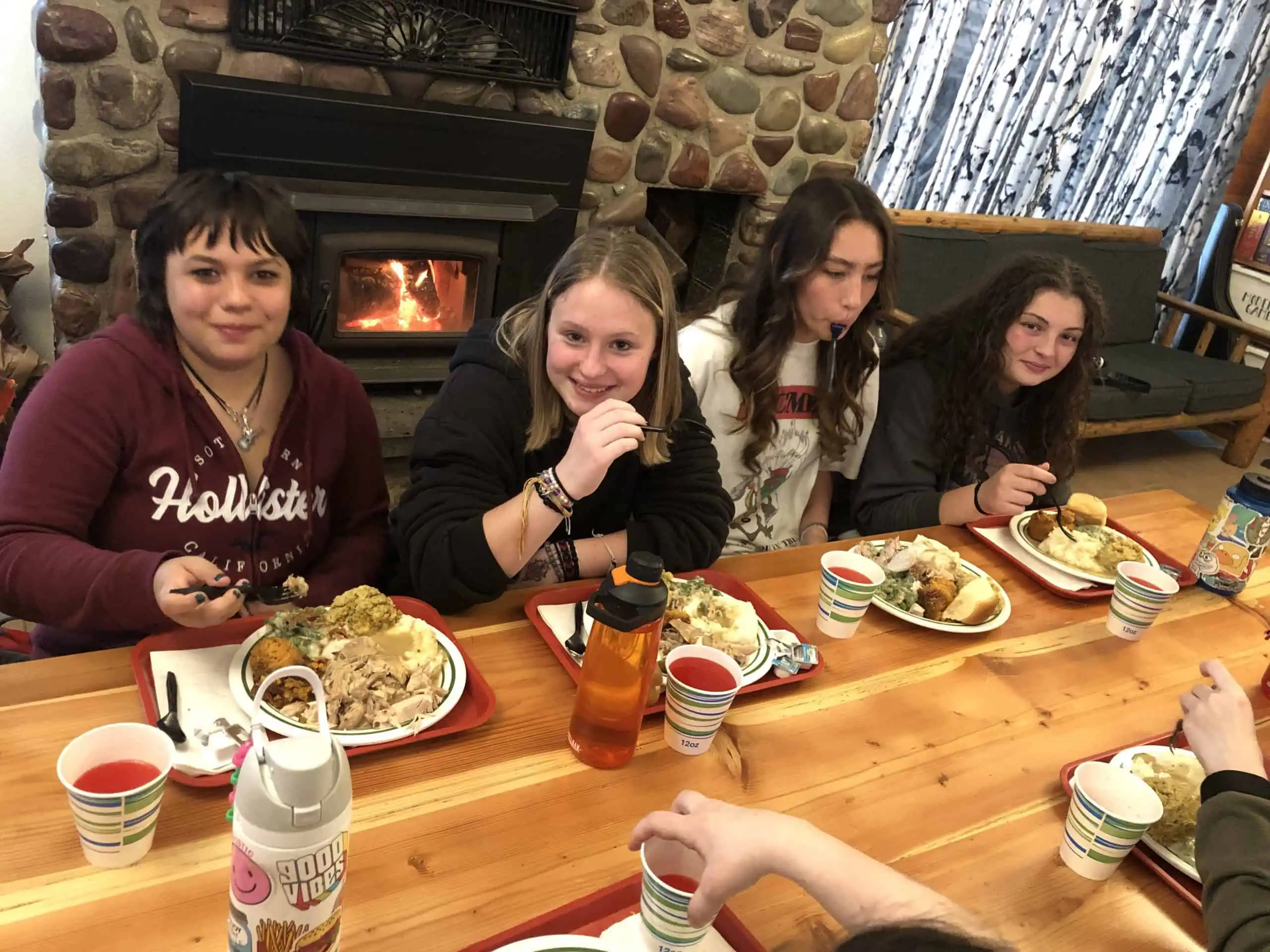 Thanksgiving at Turning Winds, Teenagers enjoying a cozy Thanksgiving meal by a stone fireplace, with a relaxed and joyful holiday atmosphere. Turning Winds, residential treatment center for teens struggling with mental health or behavioral issues.
