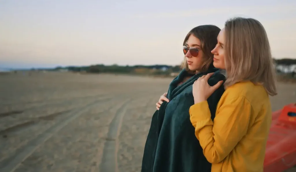Supporting Your Teen Through Rehab - A mother and teenage daughter embracing on a beach at dusk, symbolizing support and care during teen rehab and substance abuse recovery.